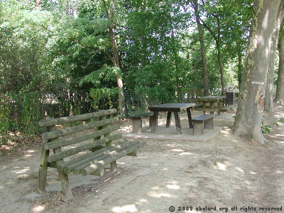 Picnic tables and bench in the dappled shade along the Canal